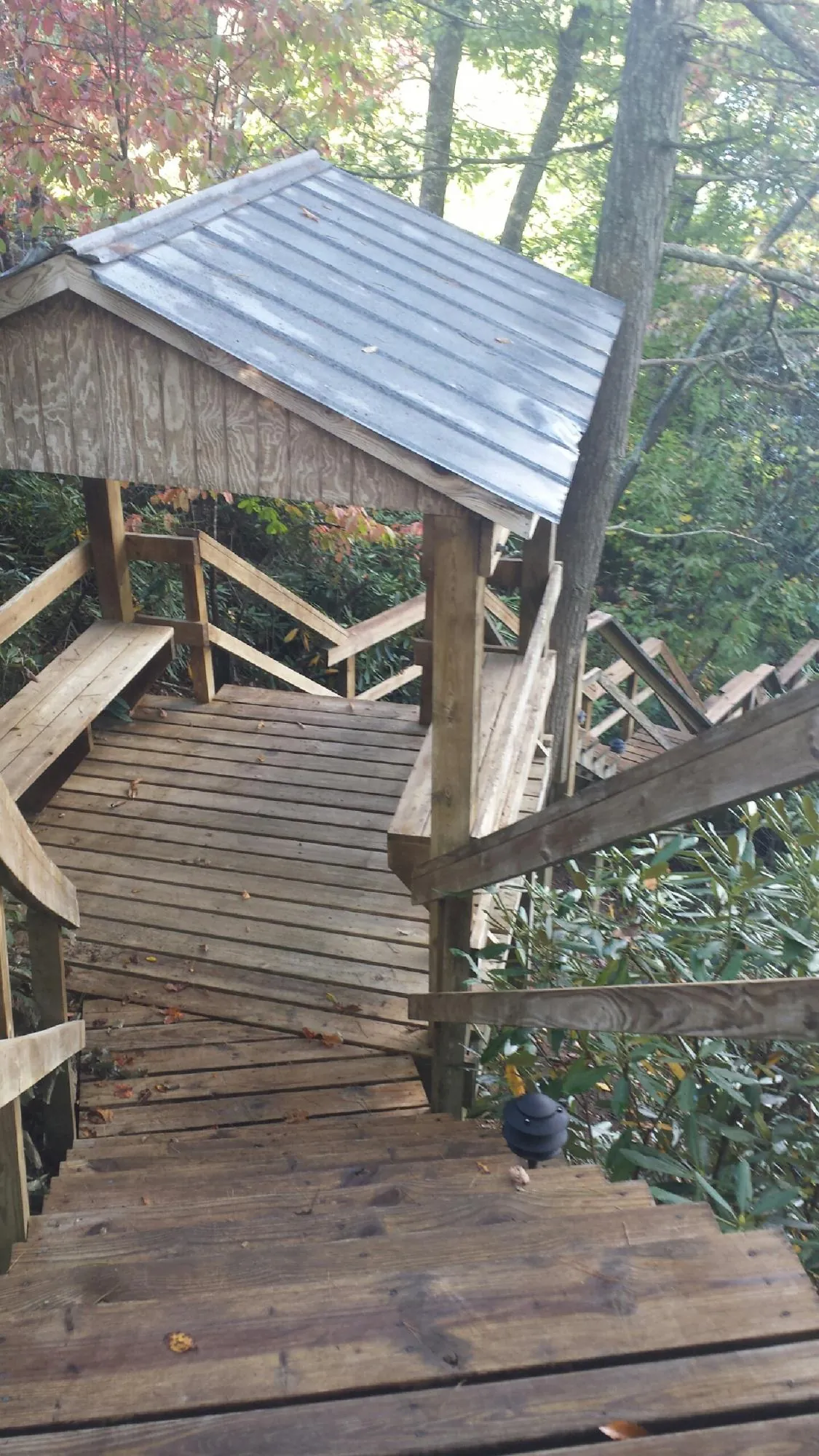Metal roofed shelter over wooden steps on a wooded walkway — Skylight Repair & Installation work by our crew in Adair